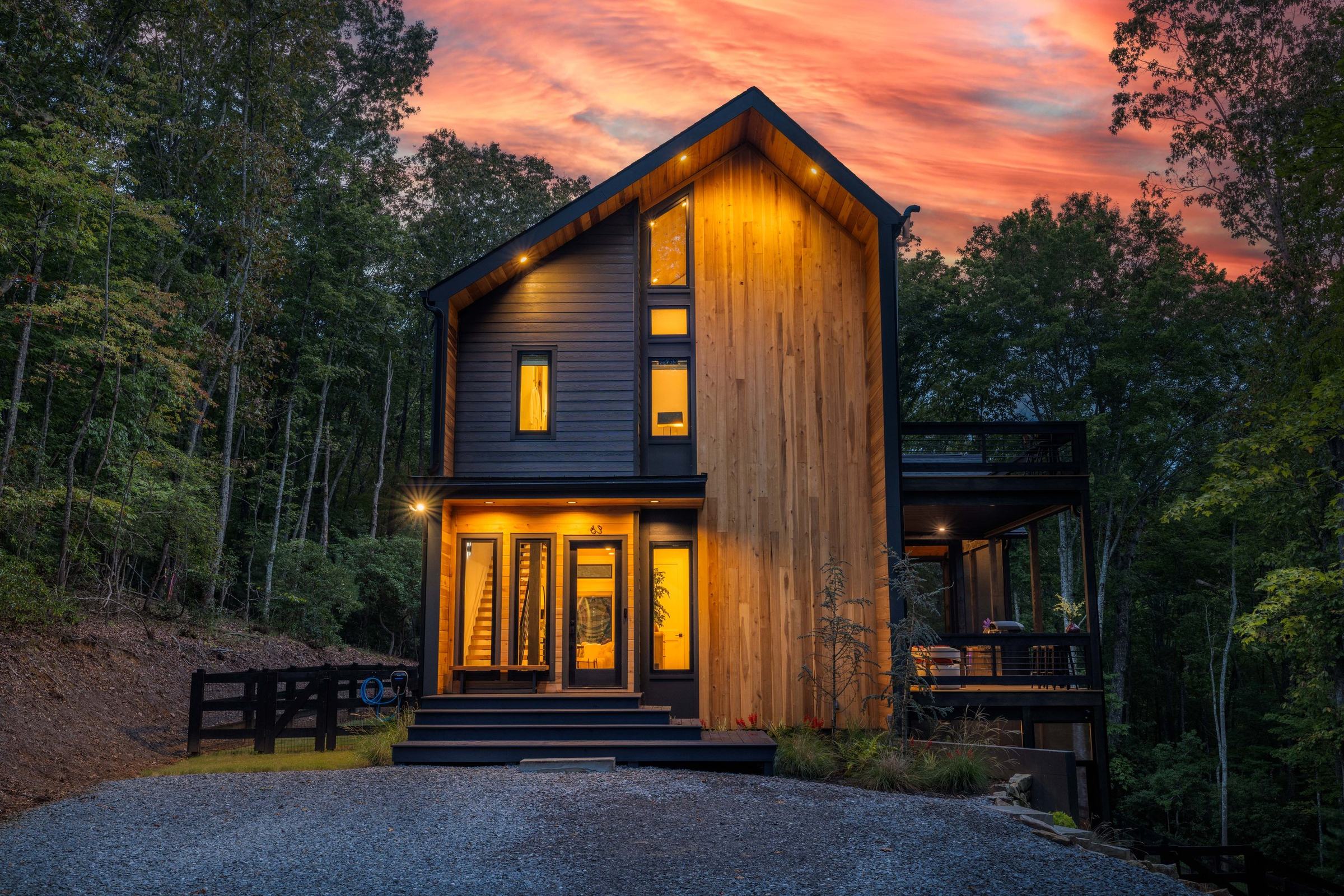 63 Laurel Trace, a Scandinavian-modern home in Blue Ridge, lit at dusk among the trees